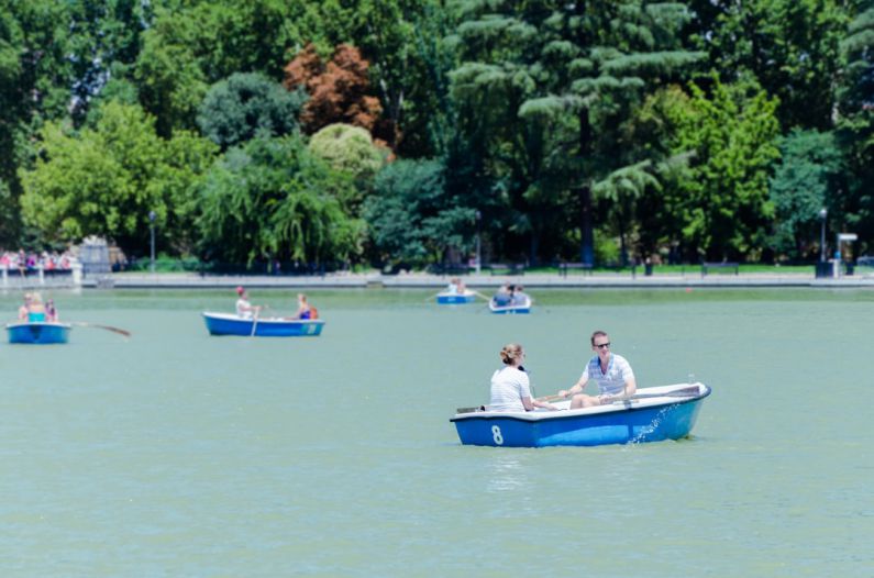 Rowing Boat - coupe riding on blue boat on calm body of water