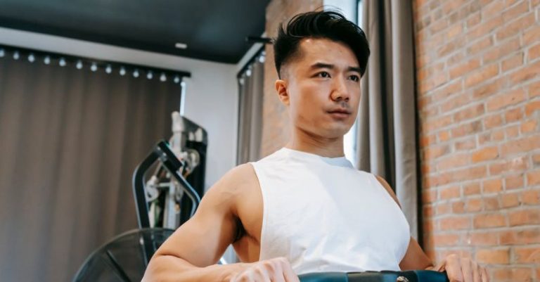 Rowing - Young Asian man using gym equipment for keeping fit