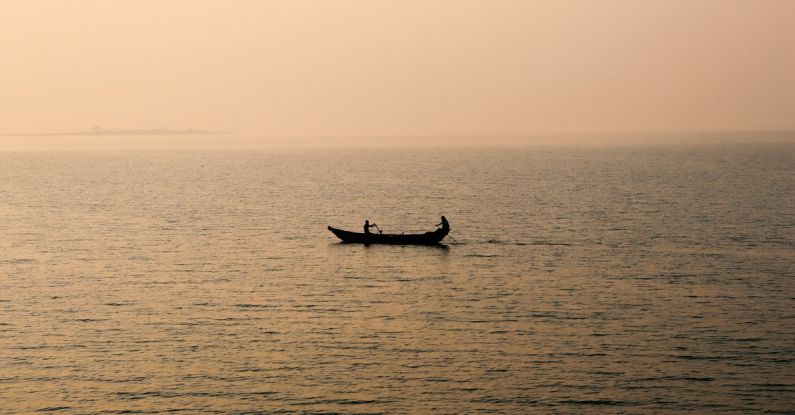 Rowing - Silhouettes of People Rowing Canoe across Sea