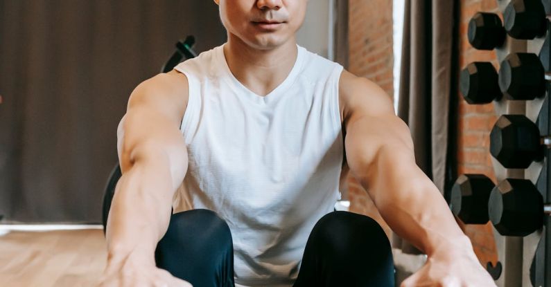 Rowing - Fit ethnic sporty young focused male working out in contemporary gym with brick walls sitting on rowing machine