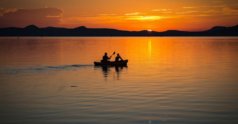 Rowing - 2 Person on Boat Sailing in Clear Water during Sunset