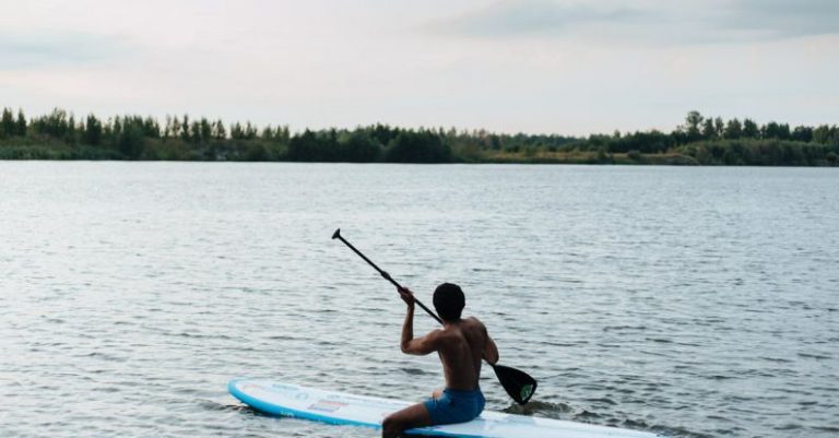 Rowing - Man Sitting on Paddleboard and Rowing
