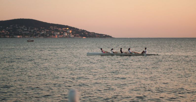 Rowing - Dawn Seascape with a Group of People Rowing in a Boat