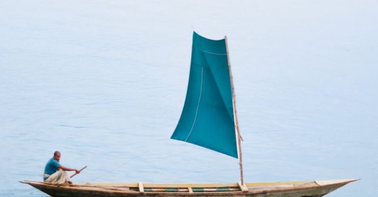 Rowing - Man on Boat with Sail on Lake