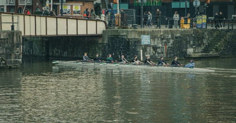 Rowing - A group of people are rowing a boat down a river