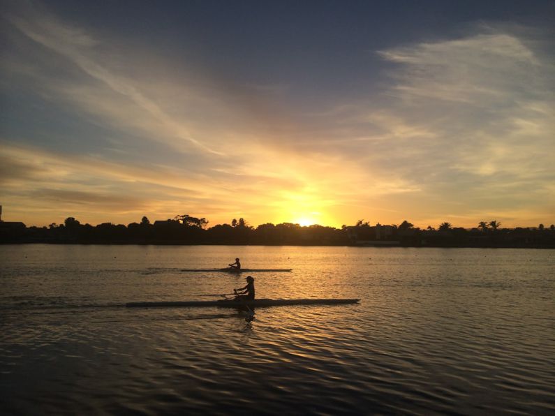 Rowing - two people silhouette on body of water during golden hour