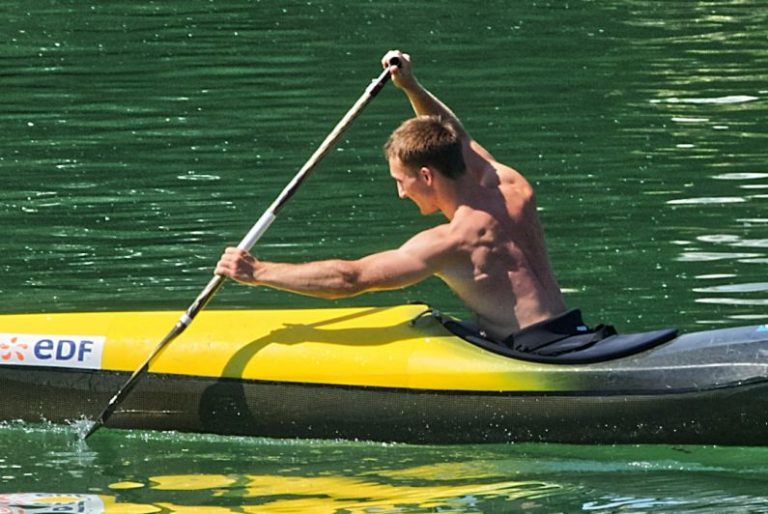 Rowing - man in black shorts riding yellow kayak on green water during daytime