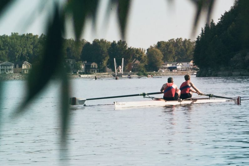Rowing - two men riding on boat on calm body of water