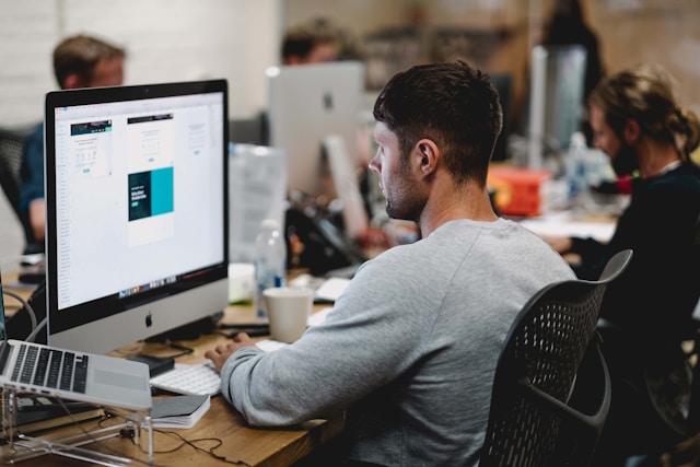 man-in-gray-sweatshirt-sitting-on-chair-in-front-of-imac